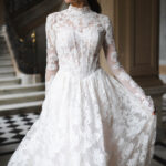 Fabric is Sheet lace, silhouette is Fitted jacket overlay, neckline is High neck, sleeve style is Long sleeves, train is None (overlay jacket only), waistline is Natural, fitted to gown, embellishment is Intricate lace appliqué, back is Sheer illusion with button closure, color is Ivory/Nude, style is Regal, Vintage-inspired, Detachable, versatile for ceremony-to-reception transformation