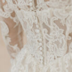 Fabric is Sheet lace, silhouette is Fitted jacket overlay, neckline is High neck, sleeve style is Long sleeves, train is None (overlay jacket only), waistline is Natural, fitted to gown, embellishment is Intricate lace appliqué, back is Sheer illusion with button closure, color is Ivory/Nude, style is Regal, Vintage-inspired, Detachable, versatile for ceremony-to-reception transformation