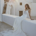 Fabric is Crepe & Lace, silhouette is Sheath, neckline is Illusion Plunge, sleeve style is Spaghetti Straps, train is Chapel with Lace Appliqué, waistline is Natural, embellishment is Floral Lace Appliqué, back is Illusion Low Back, color is Ivory/Nude, style is Modern Romantic, Sheer bodice, Button-back detailing, Lightweight crepe skirt