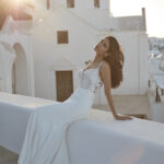 Fabric is Crepe & Lace, silhouette is Sheath, neckline is Illusion Plunge, sleeve style is Spaghetti Straps, train is Chapel with Lace Appliqué, waistline is Natural, embellishment is Floral Lace Appliqué, back is Illusion Low Back, color is Ivory/Nude, style is Modern Romantic, Sheer bodice, Button-back detailing, Lightweight crepe skirt