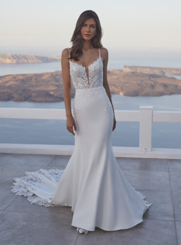 Fabric is Crepe & Lace, silhouette is Sheath, neckline is Illusion Plunge, sleeve style is Spaghetti Straps, train is Chapel with Lace Appliqué, waistline is Natural, embellishment is Floral Lace Appliqué, back is Illusion Low Back, color is Ivory/Nude, style is Modern Romantic, Sheer bodice, Button-back detailing, Lightweight crepe skirt