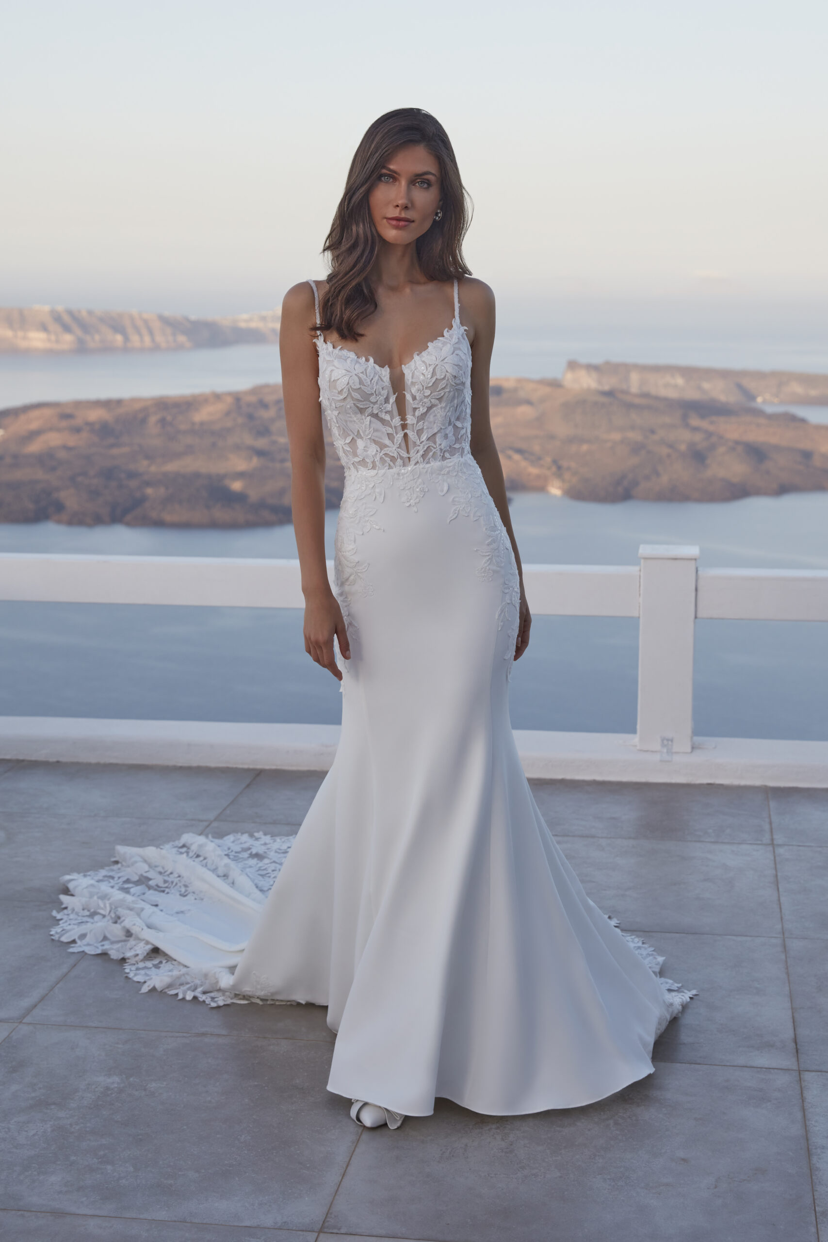 Fabric is Crepe & Lace, silhouette is Sheath, neckline is Illusion Plunge, sleeve style is Spaghetti Straps, train is Chapel with Lace Appliqué, waistline is Natural, embellishment is Floral Lace Appliqué, back is Illusion Low Back, color is Ivory/Nude, style is Modern Romantic, Sheer bodice, Button-back detailing, Lightweight crepe skirt