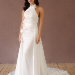 Fabric is Satin, silhouette is Fit and Flare / Modified A-Line, neckline is Halter, sleeve style is Sleeveless, train is Chapel Train, waistline is Natural Ruched, embellishment is 3D Floral Appliqué, back is Low V-Back, color is Ivory, style is Modern Minimalist Romance, Smooth satin with 3D floral details and a removable train for two distinct bridal looks.