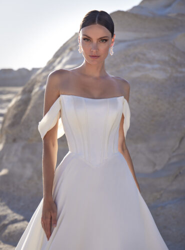 Fabric is Satin & Chiffon, silhouette is A-line, neckline is Cat eye neckline, sleeve style is Off-the-shoulder, train is Chapel, waistline is Basque, embellishment is Covered buttons, back is Button-up back, color is Ivory, style is Minimalist Romance, Boned bodice, soft drape