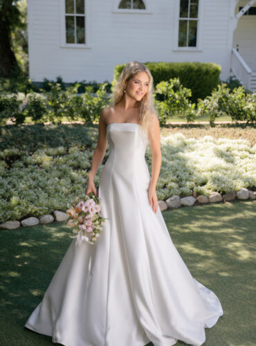 Fabric is Mikado, silhouette is A-line, neckline is Rolled strapless, sleeve style is Strapless, train is Chapel, waistline is Natural, embellishment is Minimalist, structured, back is Lace-up corset, color is Ivory, style is Modern classic, Clean lines, elegant tailoring