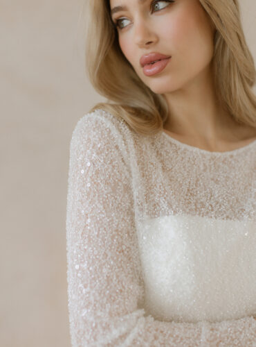 Fabric is Beaded lace / Sequin lace, silhouette is Fitted jacket, neckline is Bateau, sleeve style is Long sleeves, train is None, waistline is Natural, embellishment is Beading / Sequins, back is Buttoned back, color is Ivory, style is Classic elegance, Sheer overlay / Bridal jacket