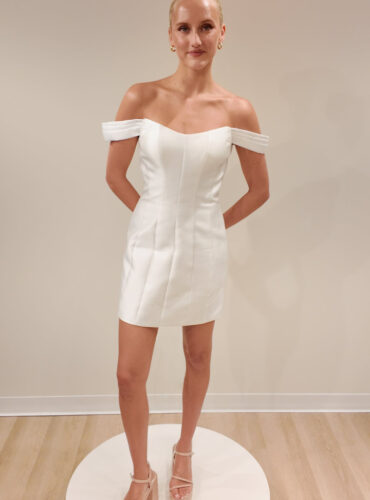 Fabric is Satin, silhouette is Sheath Mini, neckline is Sweetheart, sleeve style is Off-Shoulder, train is No Train, waistline is Natural, embellishment is Minimalist, back is Zip Back, color is Ivory, style is Modern Minimalist, Structured seams, short bridal dress, clean lines